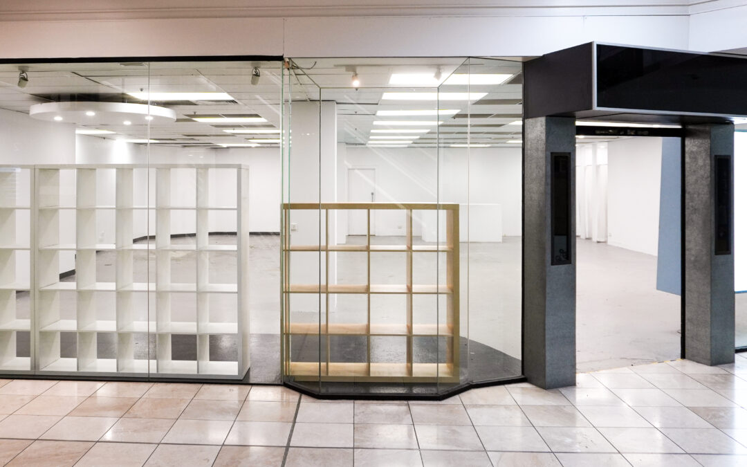 View of Shop 2.13 from outside the space, showing tiled floor, black-framed entrance and display boxes.