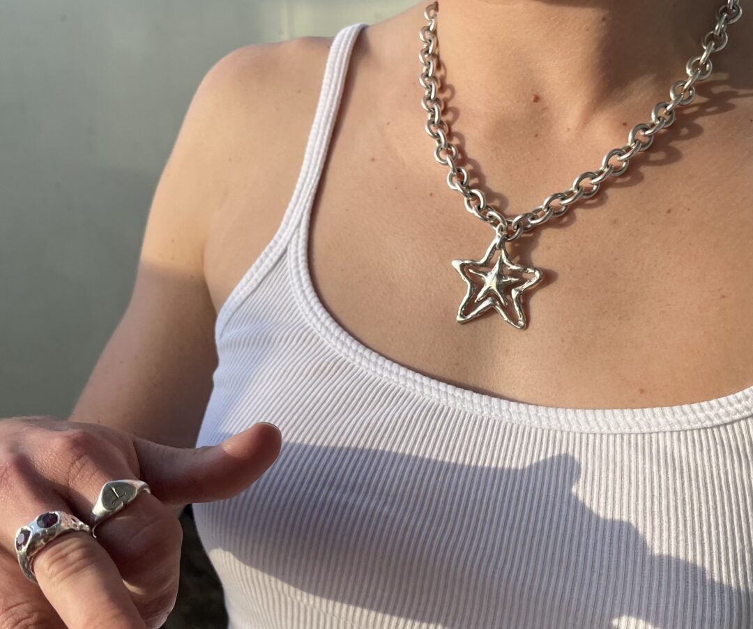 Woman wearing silver star-shaped necklace in the sun.