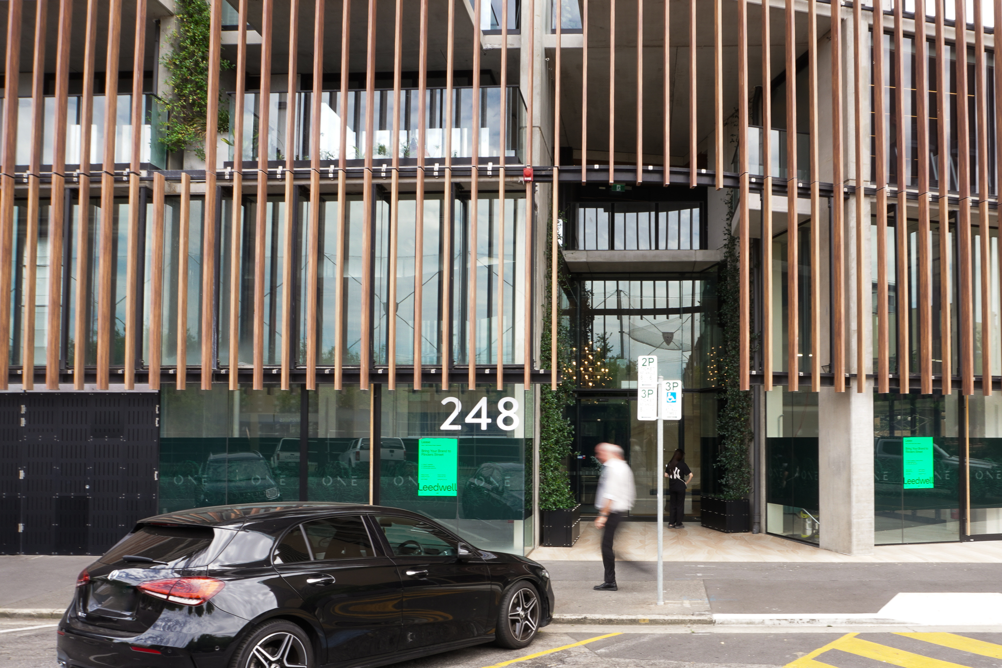 Street view of 246-248 Flinders St, a man walking past the property and on-street parking out the front of the premises.