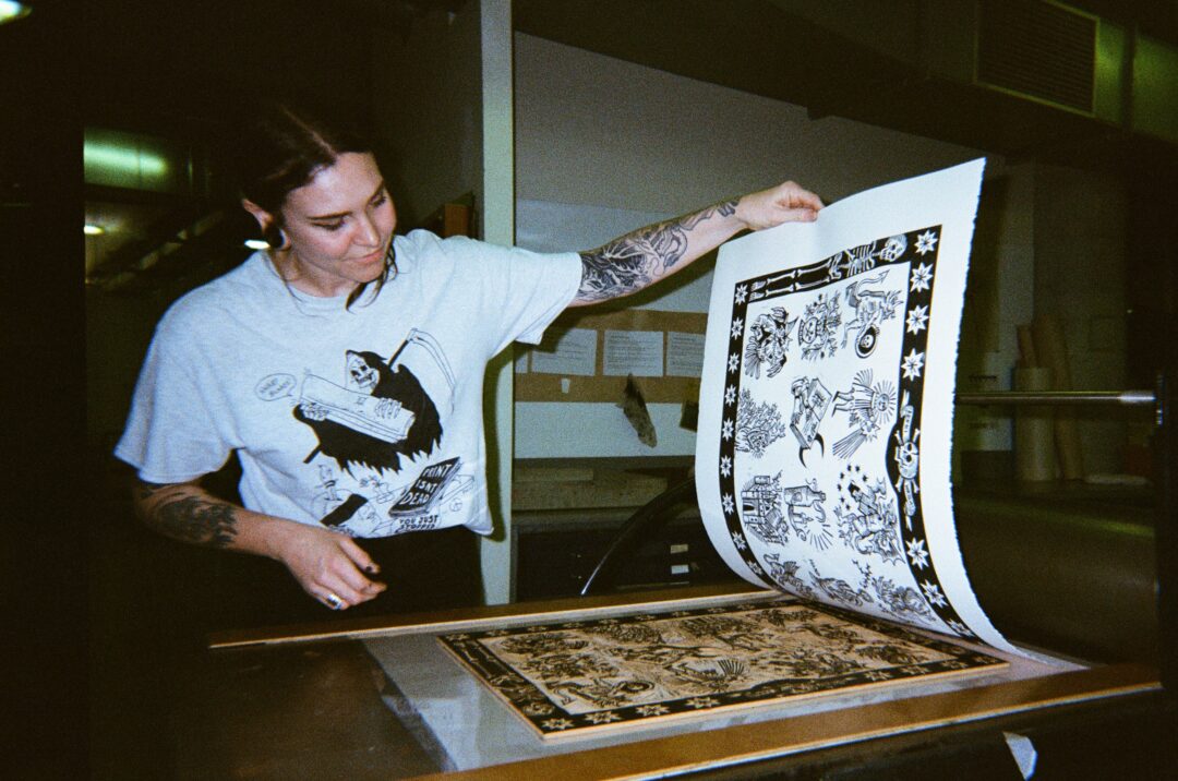 Film photo of Kerri Wright working in her printing studio, wearing a white t-shirt.