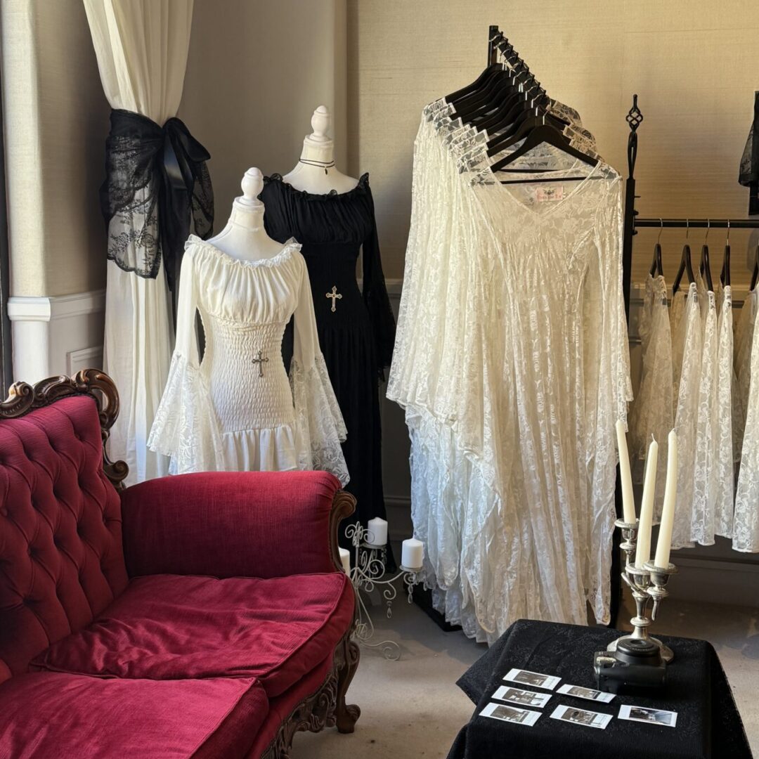 Room with red velvet couch and lacy white dresses, and a coffee table with white candles on it.