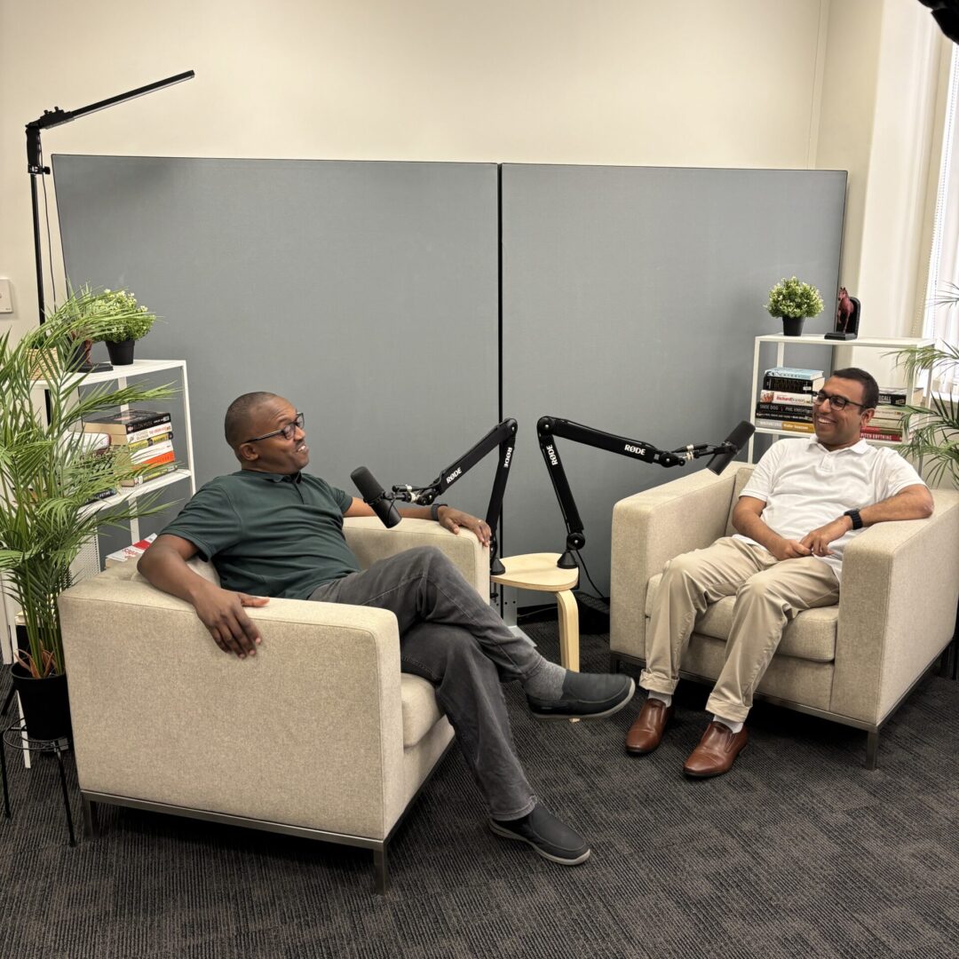 Owners of Prime Results sitting in square white chairs in their carpeted office space.