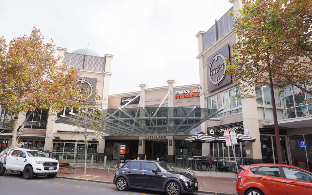 View of the shopping centre from O'Connell Street, showing parked cars, street and leafy trees.