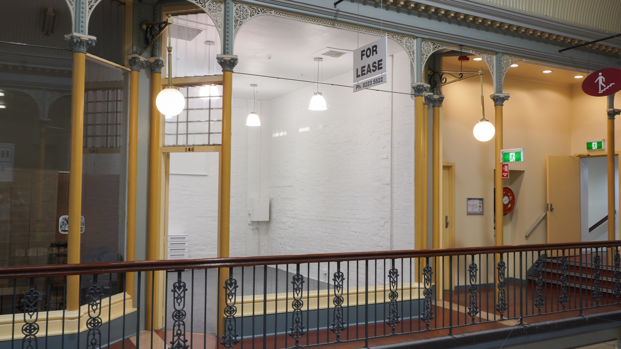 shop-146-frontage Brightly lit room with white walls and a balcony in front of it.