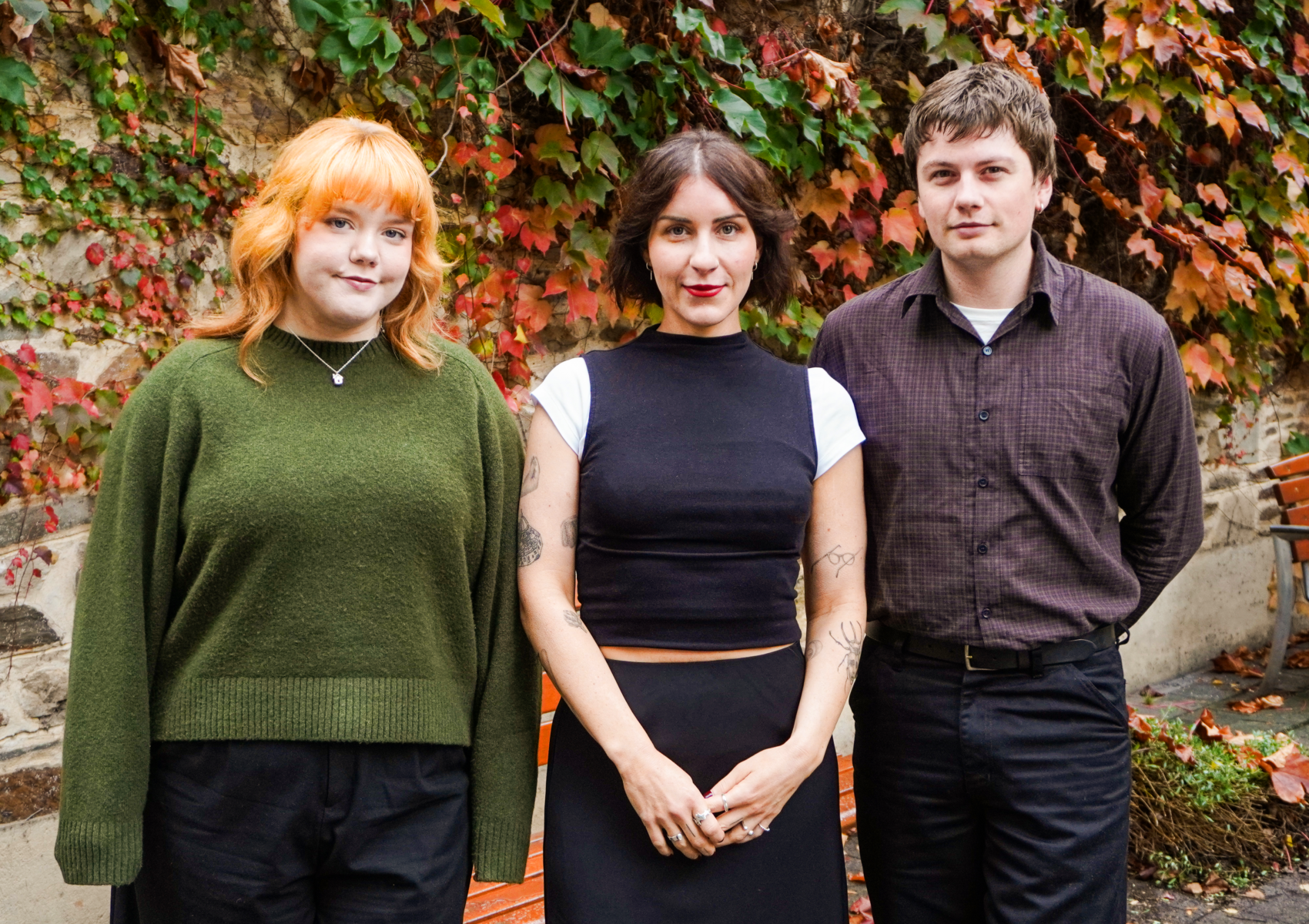 The three staff of Renew Adelaide standing in front of an Autumnal leafy brick wall.