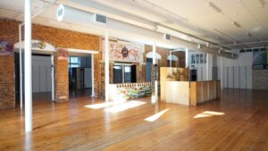 Large open-plan commercial space with polished timber floors, exposed red brick walls, high ceilings and abundant natural light.