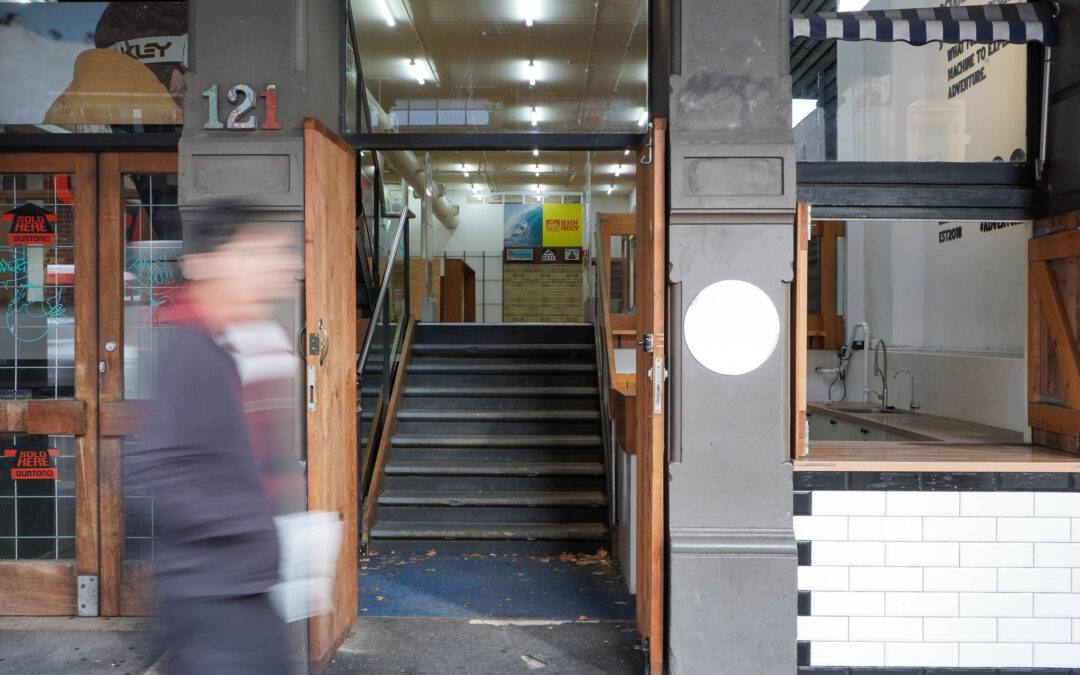 Front entrance to building with hold-in-the-wall kiosk to the right.