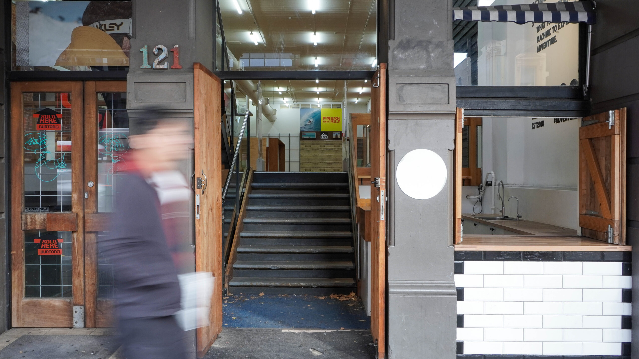 Front entrance to building with hold-in-the-wall kiosk to the right.